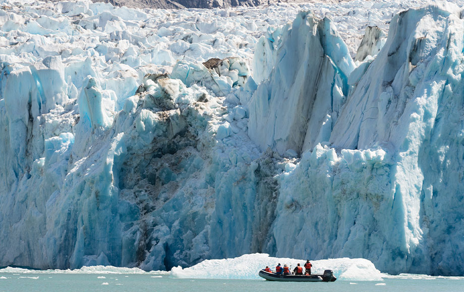 Skiff next to giant glacier